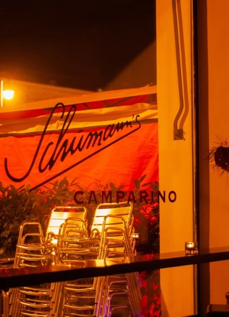 Eventfotografie in München - stimmungsvolle Abendaufnahme mit beleuchtetem Schriftzug und gestapelten Bistrostühlen vor Veranstaltungsort