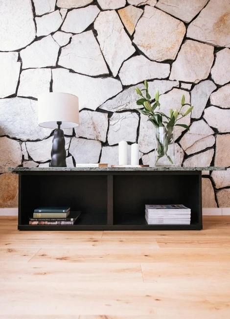 Interieurfotografie in München - moderne Wohnraumaufnahme mit Natursteinwand, Sideboard und dekorativer Vase